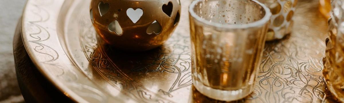 Gouden theelichtjes op een koperen schaal in zacht daglicht